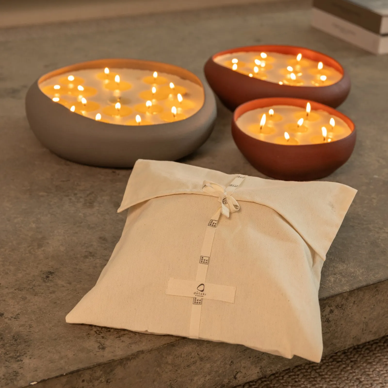 Three Doteki bowls lit, with the linen gift bag in front